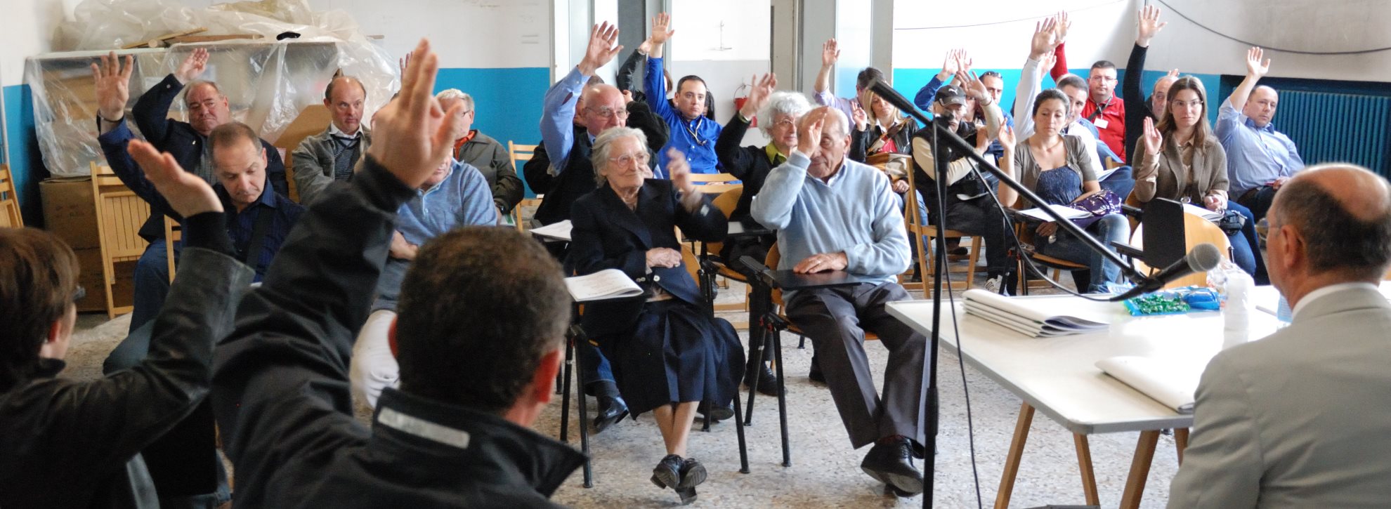 La foto immortala un momento assembleale dove i soci votano per alzata di mano